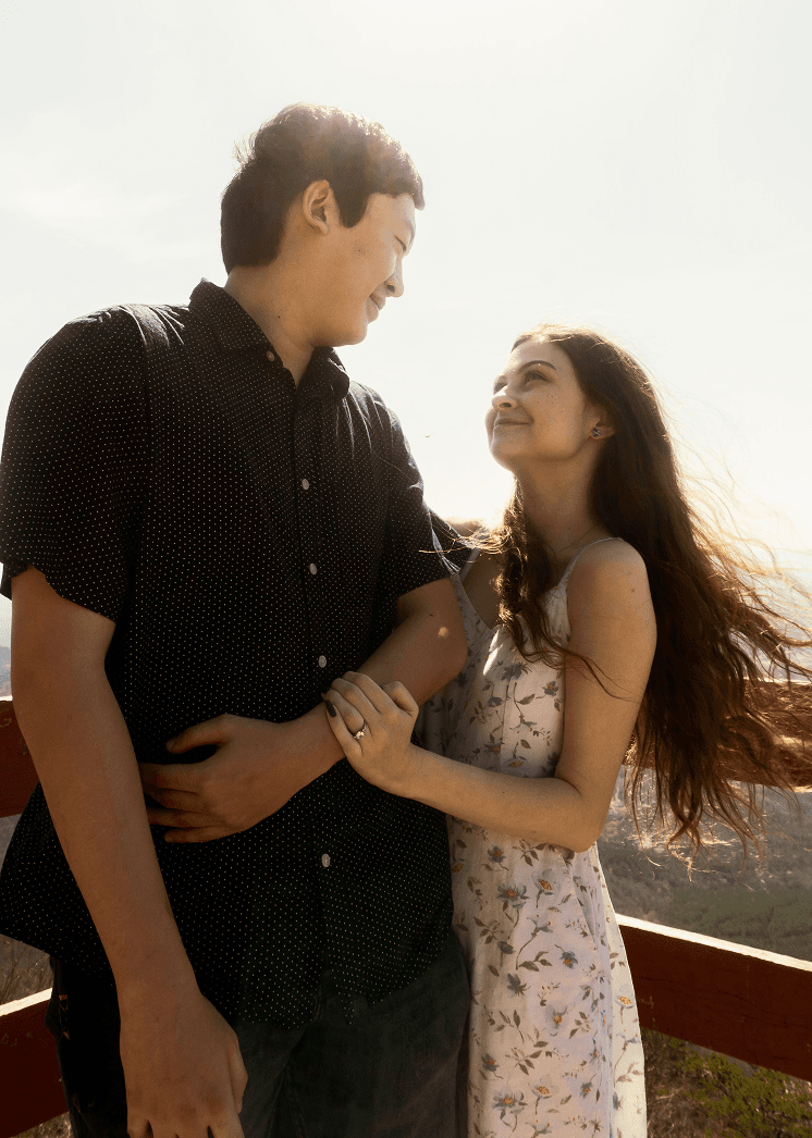A portrait of Lillian and Max holding eachother, showing Lillian's engagement ring